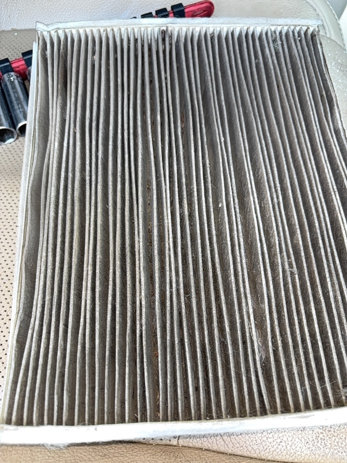 Severely dirty cabin air filter from a customer vehicle — heavy dust and debris buildup across pleats