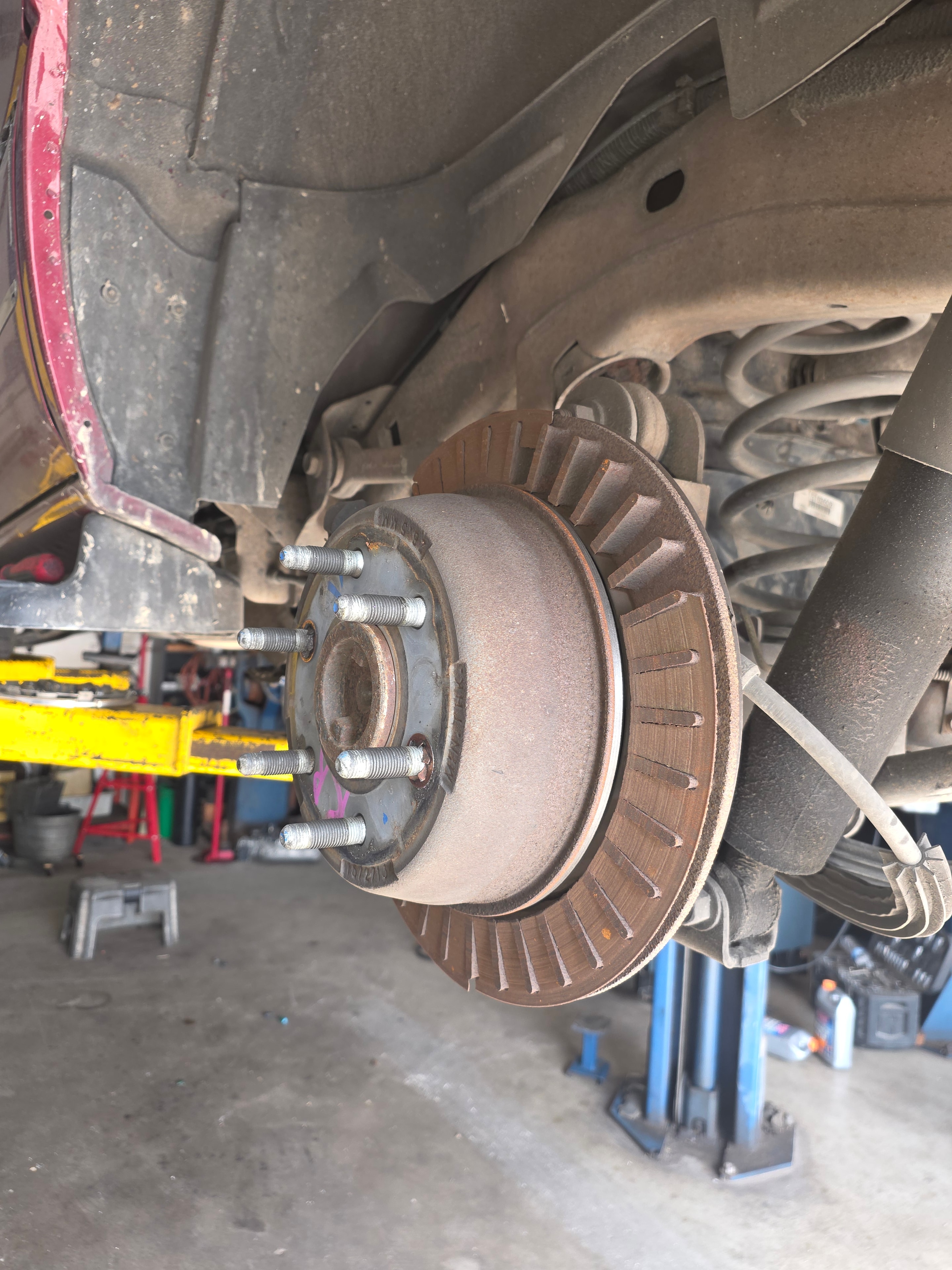 Brake rotor and hub assembly on vehicle lift during brake service at Riley Auto Care San Marcos TX