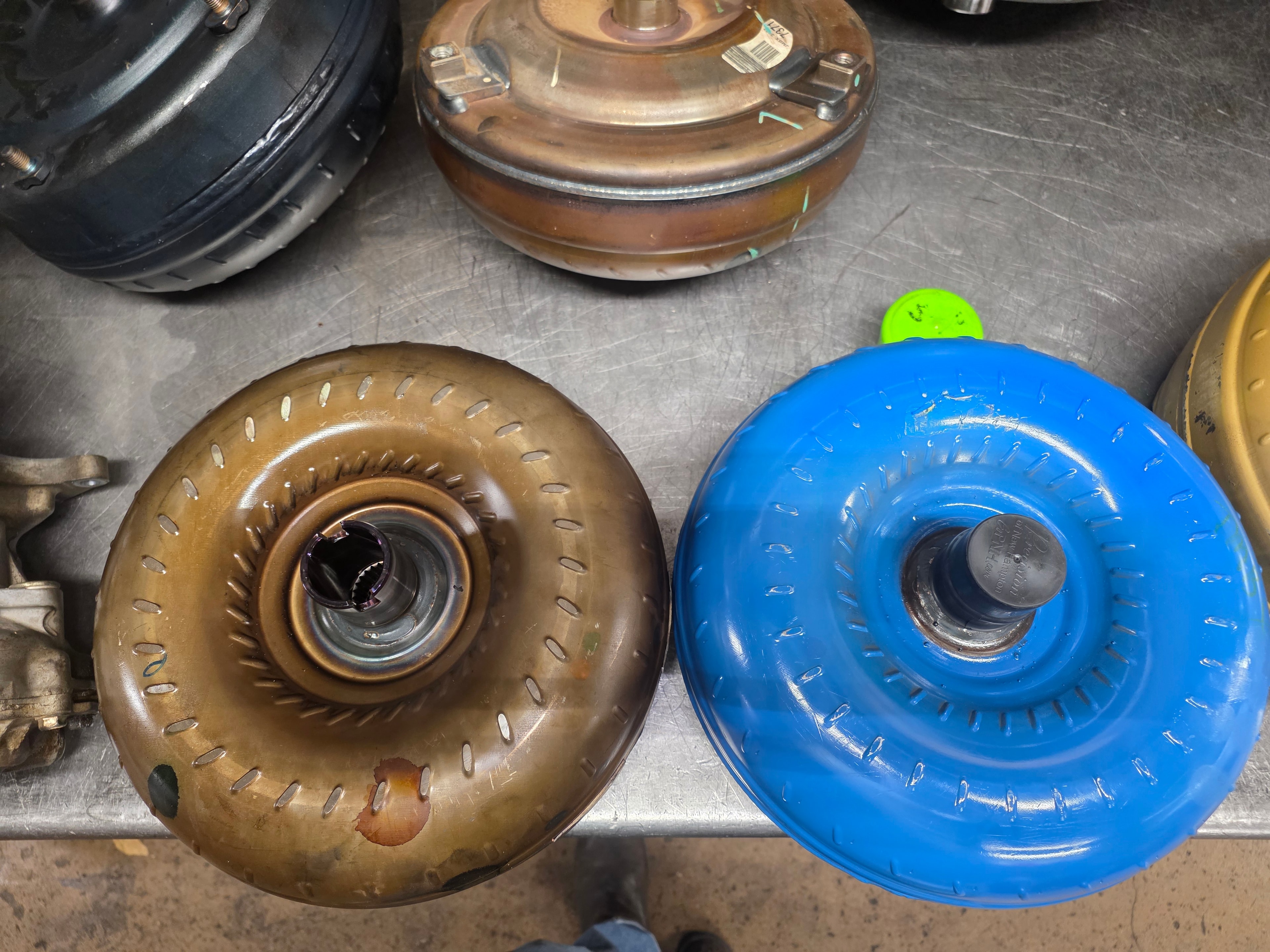 Worn OEM torque converter (brown) next to new upgraded blue torque converter at Riley Auto Care San Marcos TX