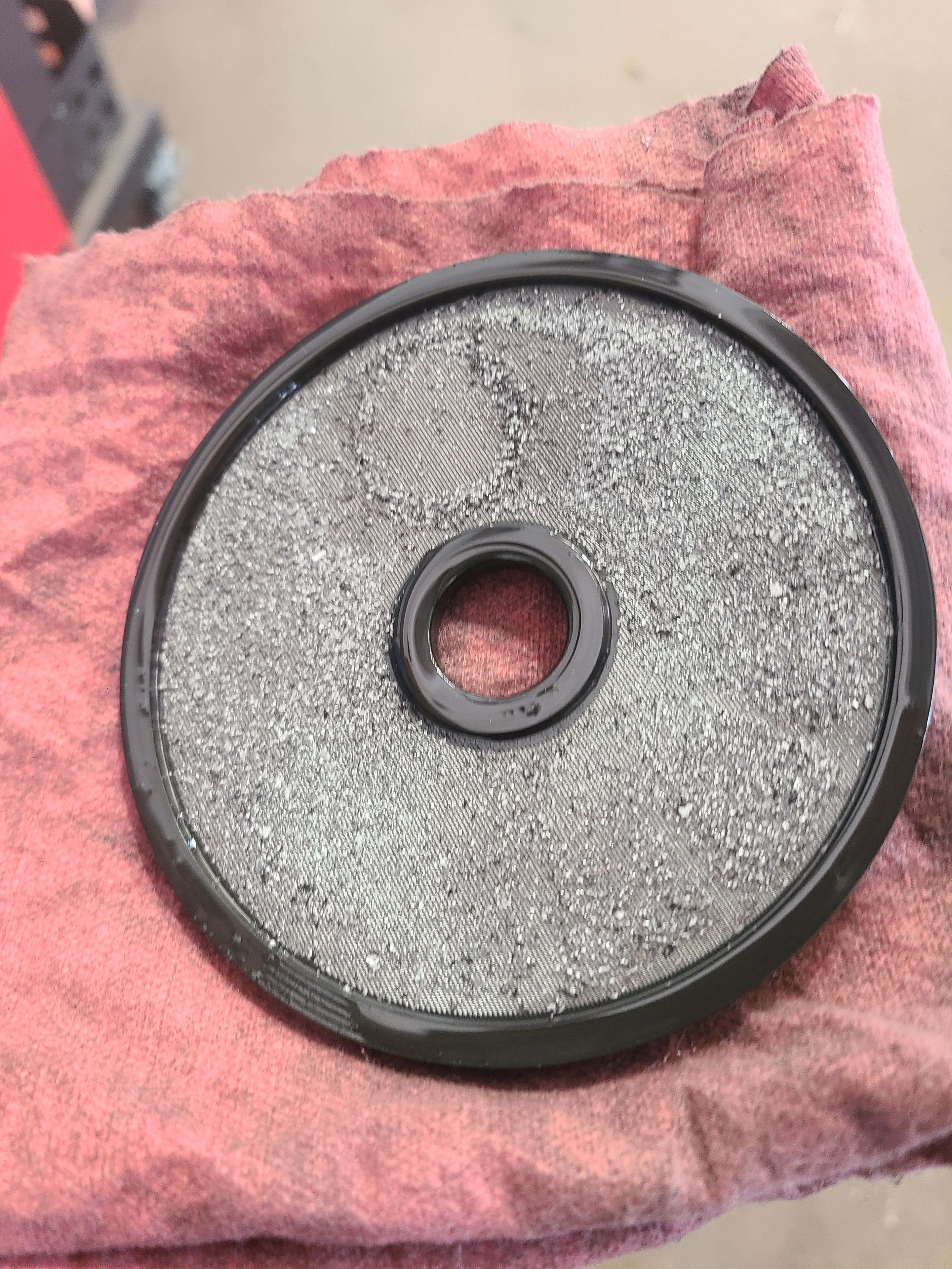 Transmission cooler flush filter screen coated in fine gray debris and metal particles removed by hot oil flush machine at Riley Auto Care San Marcos TX