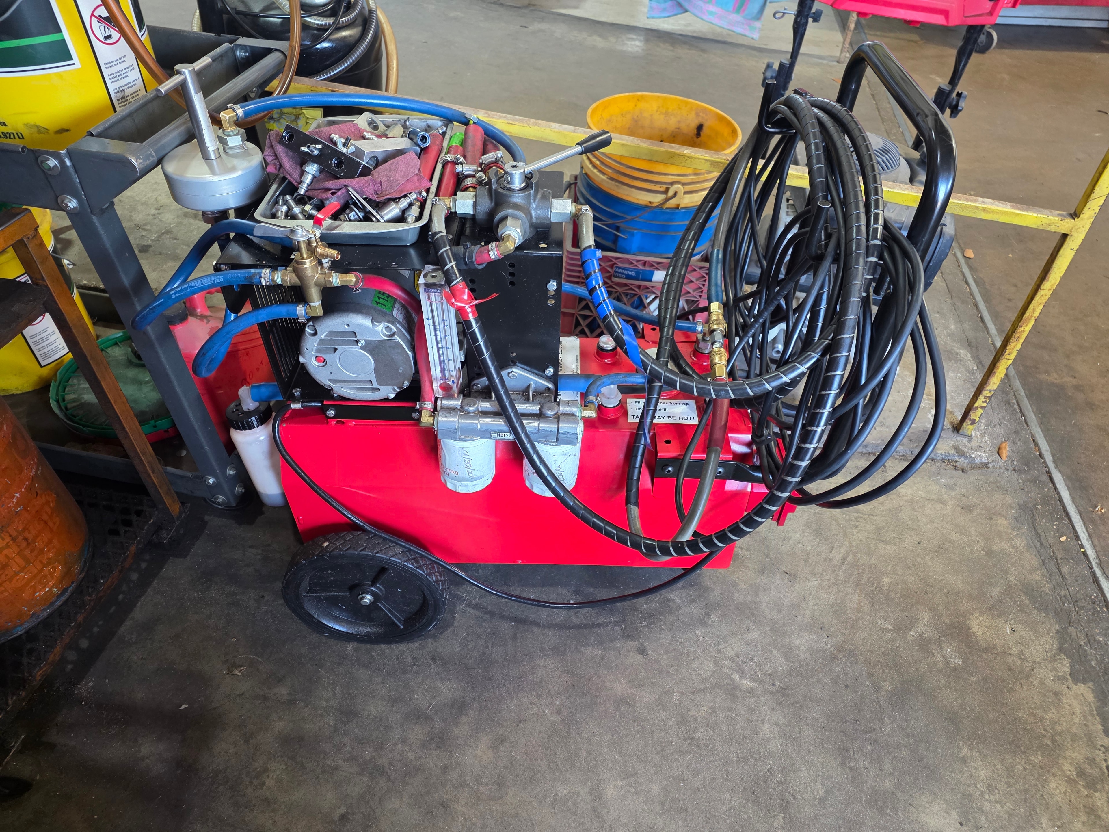 Hot oil flush machine used at Riley Auto Care & Transmissions — red cart with pump, dual inline filters, blue and black hoses for circulating heated ATF through transmission coolers in San Marcos TX